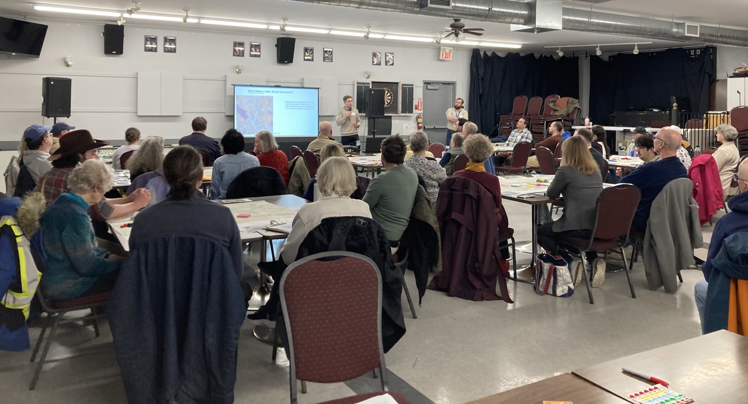 Photo of residents sitting at tables while a planner is presenting