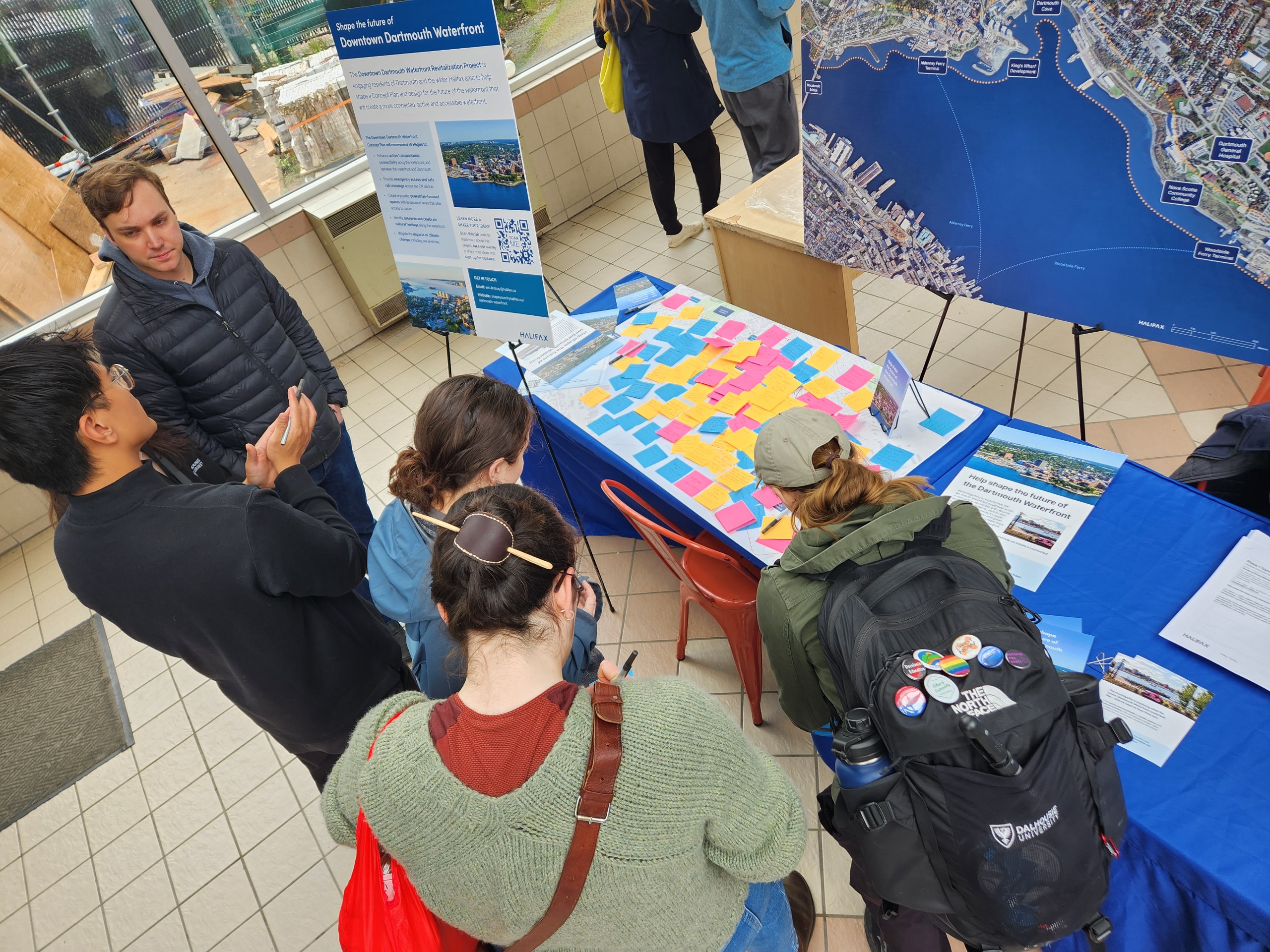 Engagement pop up at Alderney Landing Saturday market. People are writing their feedback in front of engagement boards on a table.